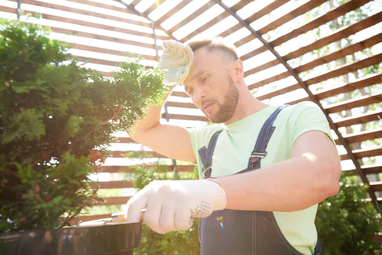 A man sweating and working in a greenhouse.