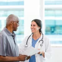 A young female doctor talking to an older male patient.